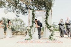 a bride and groom kissing under an outdoor wedding ceremony