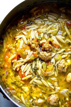 a pot filled with pasta and meatballs on top of a stove