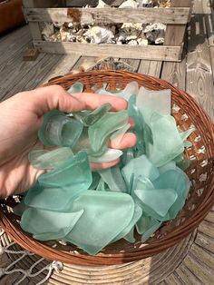 a person is holding sea glass in a basket