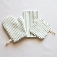 two oven mitts sitting on top of a white table next to a wooden stick