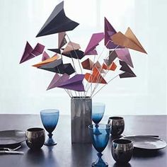 a vase filled with lots of purple and orange paper airplanes on top of a table