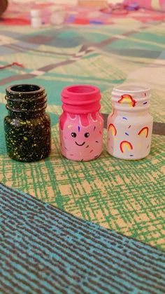 three jars sitting on top of a table covered in confetti and sprinkles