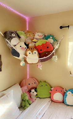 a bed with many stuffed animals on it and a hammock hanging from the ceiling