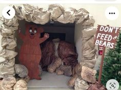 there is a fake bear in the cave with rocks and trees behind it that says don't feed bears