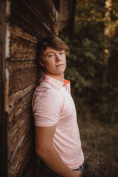 a young man leaning against a wooden wall