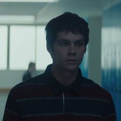 a young man standing in an office building looking at the camera while wearing a striped shirt