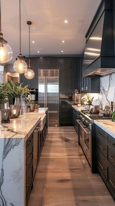 a large kitchen with marble counter tops and black cabinetry, along with hanging lights