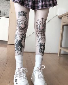 the legs and ankles of a woman with tattoos on her body, wearing white tennis shoes