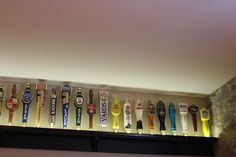 a row of beer bottles sitting on top of a shelf next to a stone wall