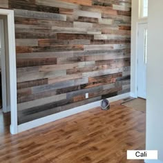 an empty room with wood planks on the wall and hard wood flooring in it