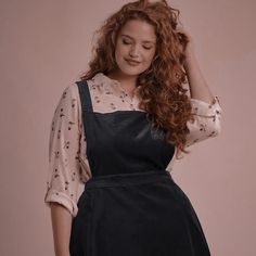 a woman with long red hair wearing a black pinafstock and polka dot blouse