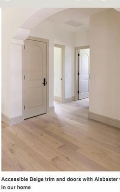 an empty room with white walls and wood floors, has a large door in the center