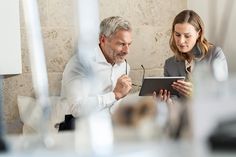 a man and woman looking at something on a tablet