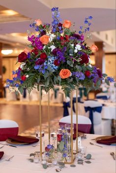 a vase filled with lots of flowers on top of a white tablecloth covered table