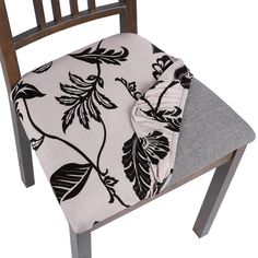 a wooden chair with a black and white floral print on the seat pad, next to a gray cushion