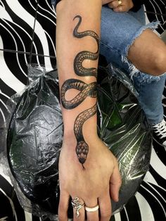 a woman's hand with a tattoo on it and a snake on the wrist