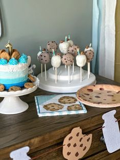 an assortment of desserts and cookies on a table in front of a cake with blue frosting