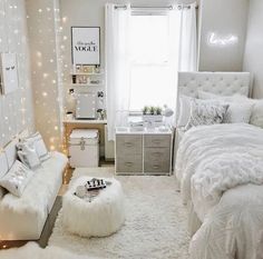 a bedroom decorated in white and gray with lights on the walls, bedding, rugs and pillows