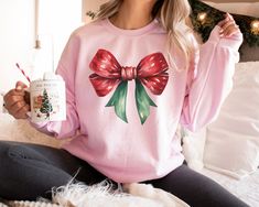 Stay on trend with this Coquette Christmas Gildan 18000 sweatshirt.  The traditional colors and feminine style of this crewneck are sure to remain a staple in your closet for years to come.  Wear as you lounge at home or to all of your holiday festivities!  Buy for yourself or make this sweater a gift for your favorite Christmas girly. PLEASE READ THROUGH ALL OF THE FOLLOWING INFORMATION.  IF YOU HAVE FURTHER QUESTIONS, WE ARE HAPPY TO HELP! Welcome to CuratedClothCo.!  Here you can find the perfect, trendy attire whether you are gifting for someone else or yourself.  We strive to provide quality merchandise and quick customer service in order to make your buying process fun and easy.  We hope you love our designs as much as we do! FREE SHIPPING ON ALL ORDERS SHIPPED WITHIN THE U.S.!! *Ord Festive Holiday Crew Neck Sweatshirt, Holiday Crew Neck Sweater As Gift, Holiday Crew Neck Sweater As A Gift, Holiday Long Sleeve Sweatshirt As Gift, Christmas Party Sweater, Christmas Apparel, Coquette Christmas, Party Sweaters, Buying Process