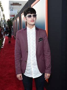 a young man wearing sunglasses standing on a red carpet at an awards event with his hands in his pockets