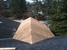 the roof of a house is covered in wood shingles and there are pine trees behind it