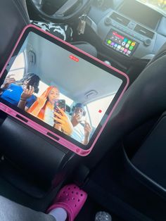 a car dashboard with two people on the screen and one person holding a cell phone