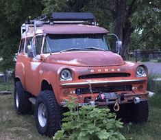 an old red truck is parked in the grass