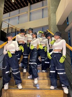 the models are dressed in blue and white outfits with green gloves on their heads, standing on some stairs