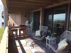 two chairs and a table on a porch with glass doors leading to the outside patio