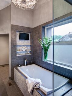 a bathroom with a large tub and a television on the wall next to the window