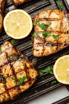 grilled pork chops with lemon slices and parsley garnish on a grill