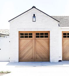 two wooden garage doors in front of a white brick building