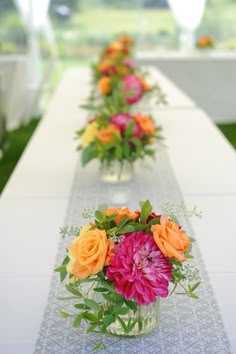 several vases filled with different colored flowers on a long table