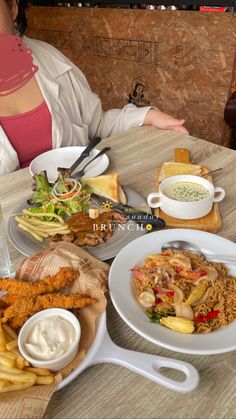 a woman sitting at a table with plates of food