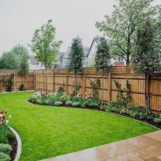 a backyard with green grass and flowers in the center, surrounded by a wooden fence