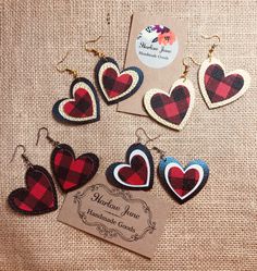 the plaid heart earrings are on display in front of a card and some other items