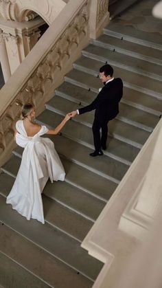 a bride and groom walking down the stairs