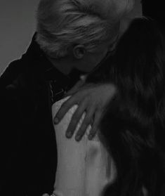 two people are hugging each other in black and white, with the woman's hair blowing back