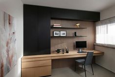 a desk with a computer on top of it in front of a wall mounted bookcase