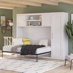 a white bed sitting under a book shelf next to a green wall