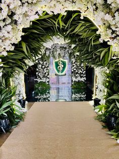 an archway decorated with white flowers and greenery