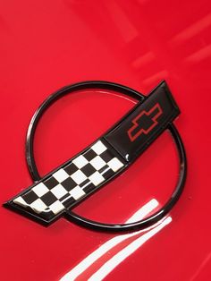 an emblem on the hood of a red car that is painted black and white checkered