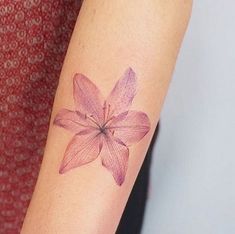 a woman's arm with a pink flower tattoo on the left side of her arm