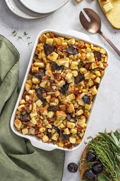 a casserole dish filled with stuffing next to bread and other food on plates