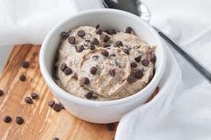 a white bowl filled with chocolate chip ice cream on top of a wooden cutting board