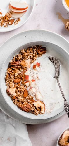 a bowl filled with granola and apple slices on top of a white tablecloth