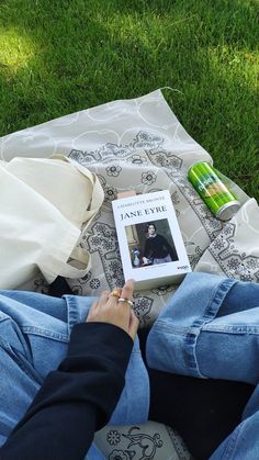 a person sitting on top of a blanket with a book in their lap next to them