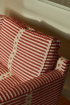 a red and white striped couch sitting next to a window