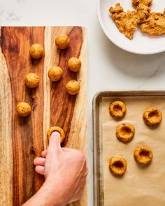 a person cutting up some food on top of a wooden board next to a bowl