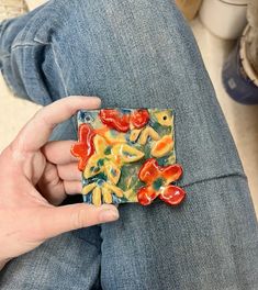 a person is sitting on the floor holding a piece of art that looks like gummy bears